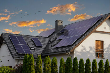 Modern house with blue solar panels on the roof. End of the day, sunset. Idyllic atmosphere.