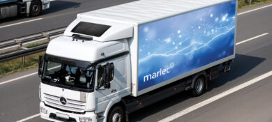 A lorry truck in a motorway with solar panel on the roof.