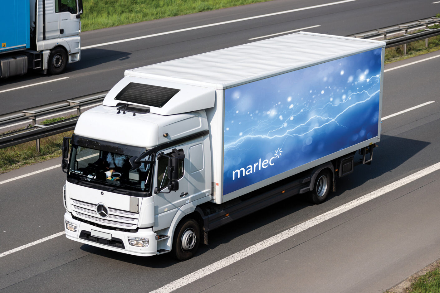 A lorry truck in a motorway with solar panel on the roof.